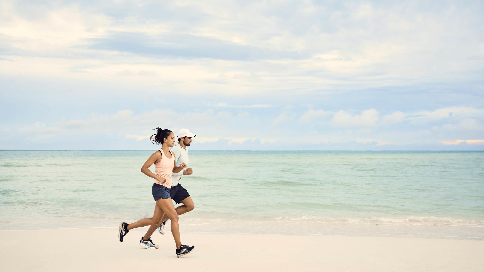 A Man And Woman Running On A Beach